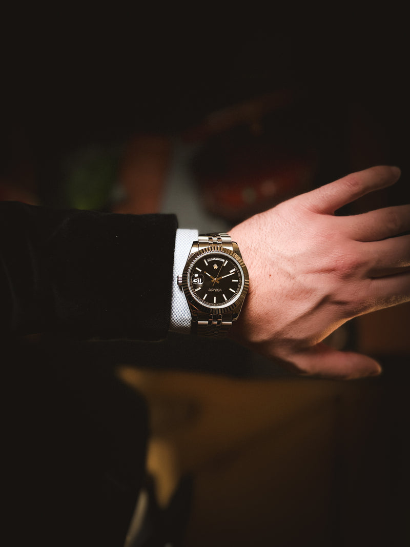 Luxury lifestyle shot of the Valenne Destro steel watch styled with men's formal wear and a light blue shirt.