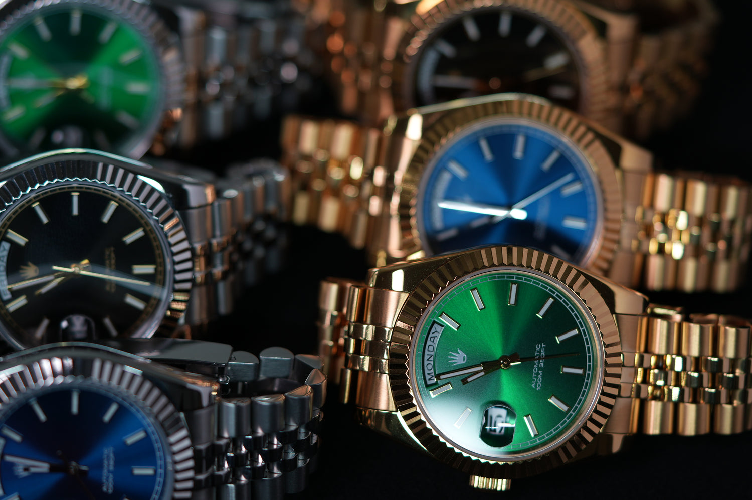 Collection of gold and black watches with green and blue faces on a dark background