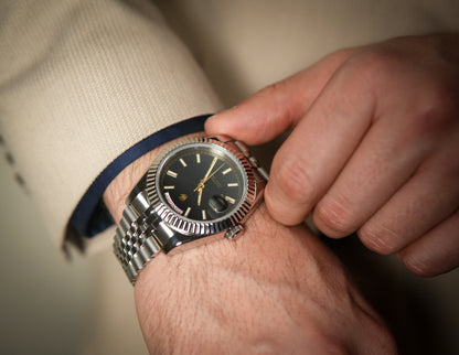 Man in a beige suit adjusting the Valenne left-handed automatic watch on his wrist.