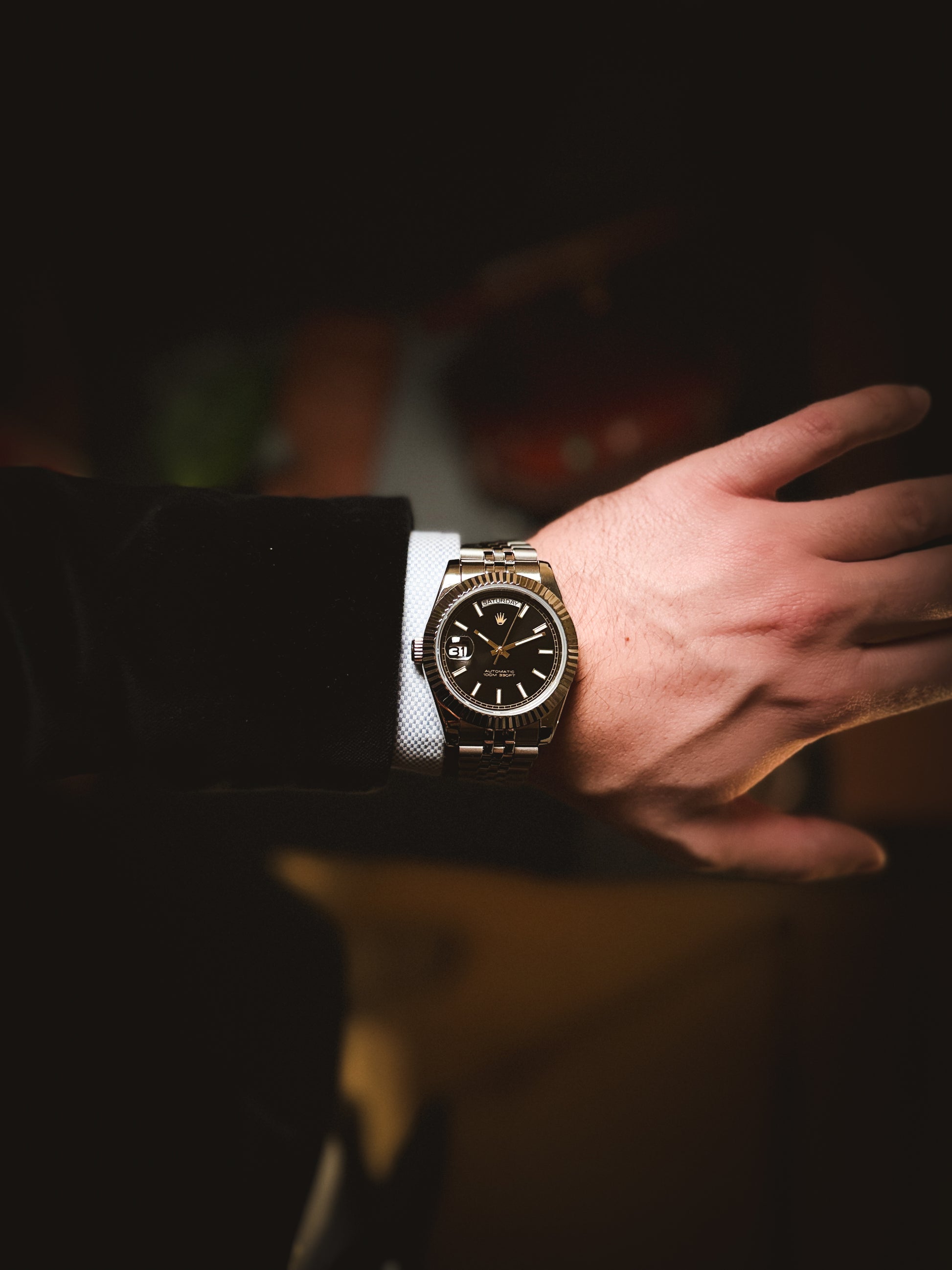 Luxury lifestyle shot of the Valenne Destro steel watch styled with men's formal wear and a light blue shirt.