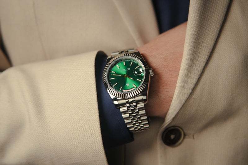 Close-up of a person wearing a destro watch with a green face and silver case.