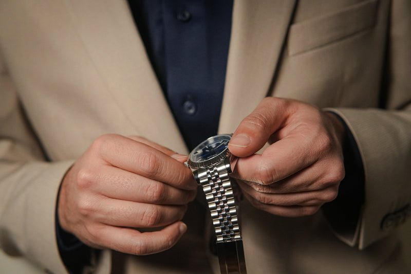 Close-up of a man adjusting the Valenne stainless steel Destro watch, featuring a left-side crown and jubilee bracelet.